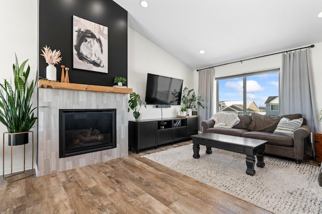 living room featuring lofted ceiling, a tile fireplace, wood finished floors, and recessed lighting