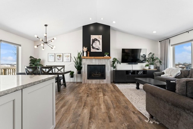 living room featuring a tile fireplace, lofted ceiling, wood finished floors, a chandelier, and recessed lighting