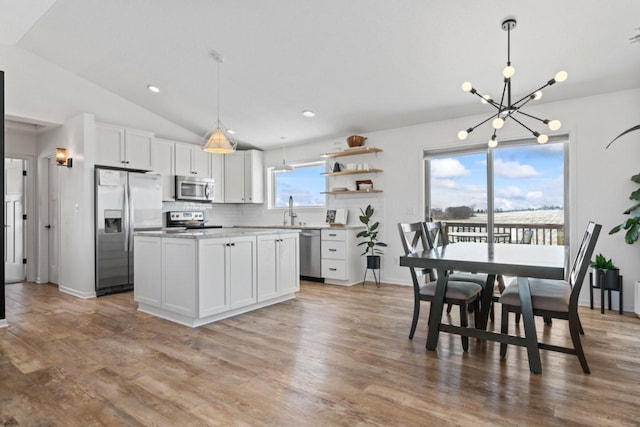 kitchen featuring white cabinets, decorative backsplash, lofted ceiling, stainless steel appliances, and a sink