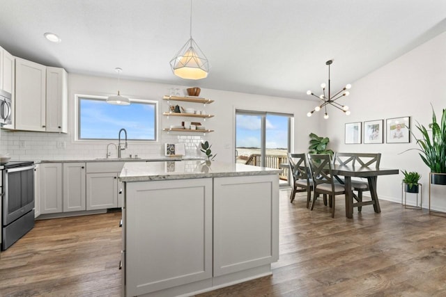 kitchen with appliances with stainless steel finishes, lofted ceiling, a wealth of natural light, and a sink