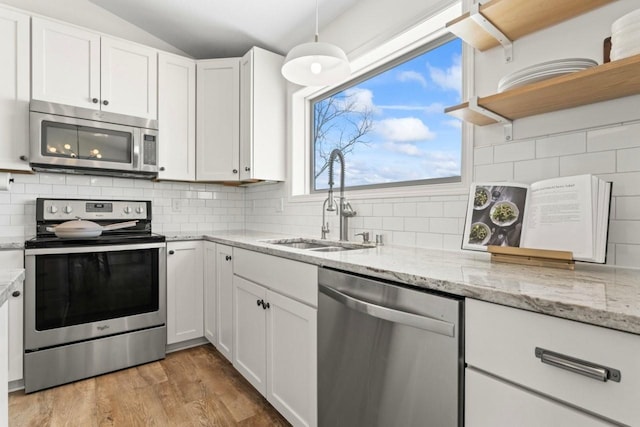 kitchen featuring stainless steel appliances, white cabinets, a sink, and light wood finished floors