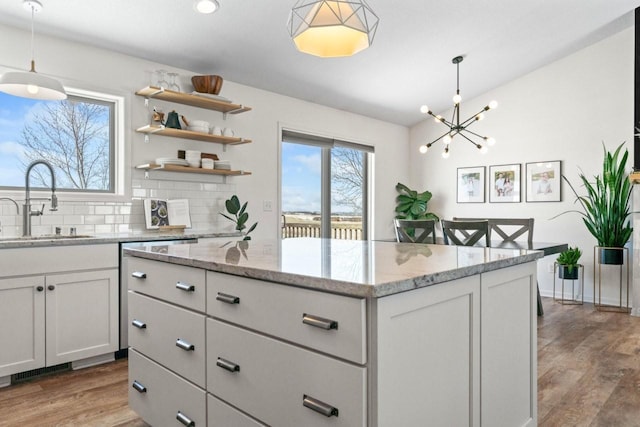 kitchen featuring decorative backsplash, a sink, light wood-style flooring, and a center island