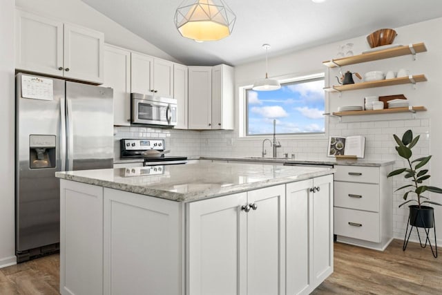 kitchen with lofted ceiling, a sink, wood finished floors, white cabinetry, and appliances with stainless steel finishes