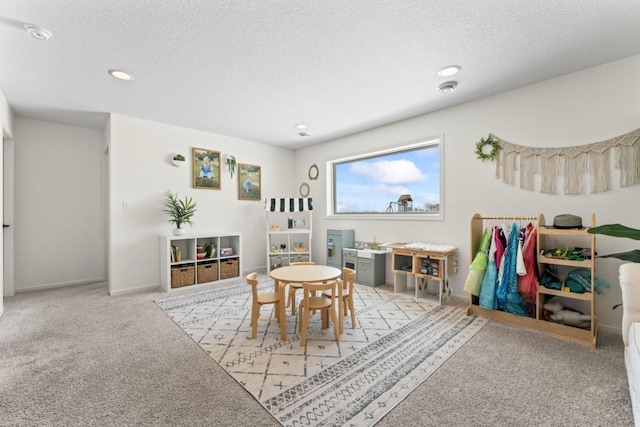 playroom featuring a textured ceiling, carpet floors, and baseboards