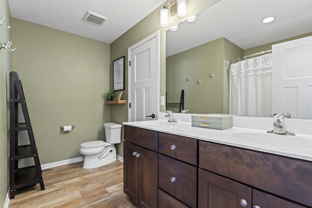 full bath featuring toilet, visible vents, a sink, and wood finished floors