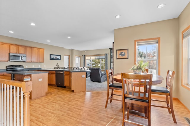 kitchen featuring a breakfast bar area, stainless steel appliances, a center island, kitchen peninsula, and light wood-type flooring