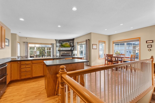 kitchen with sink, a stone fireplace, light hardwood / wood-style floors, and a kitchen island