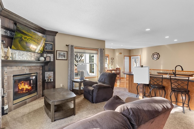 carpeted living room with sink and a tile fireplace