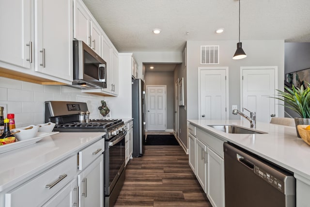 kitchen with sink, appliances with stainless steel finishes, tasteful backsplash, decorative light fixtures, and white cabinetry