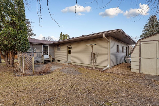 rear view of property featuring a storage unit and a sunroom