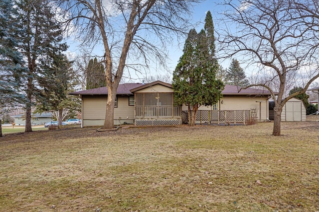 rear view of house with a yard, a storage unit, and a sunroom