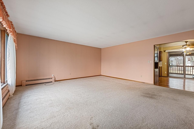 carpeted spare room with a baseboard radiator and ceiling fan