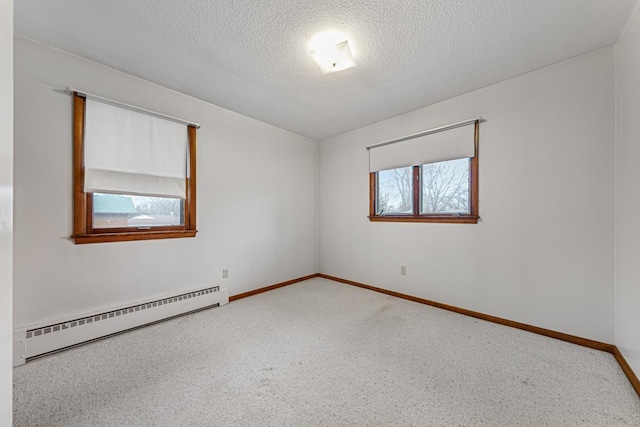 empty room featuring a baseboard heating unit and a textured ceiling