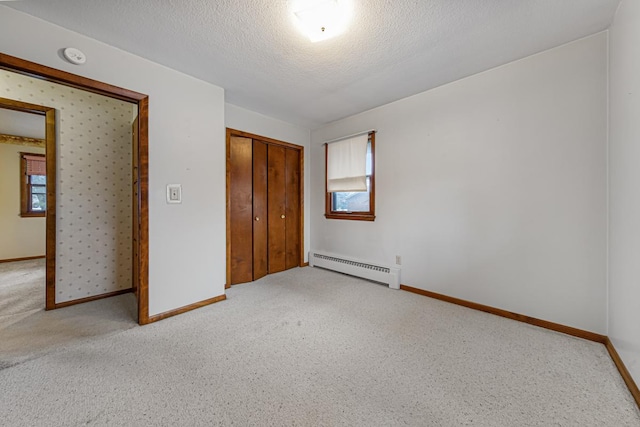 unfurnished bedroom with light carpet, a closet, baseboard heating, and a textured ceiling