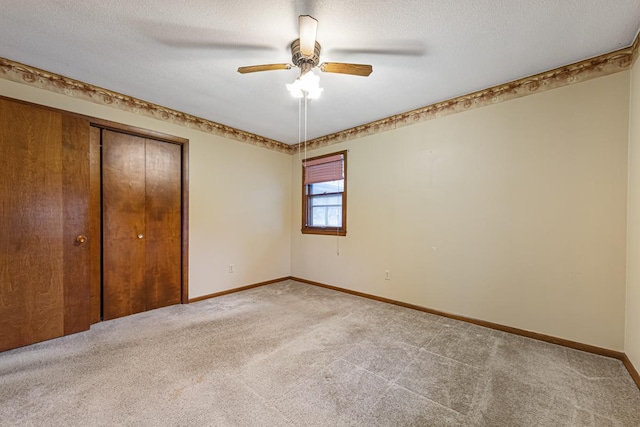 unfurnished bedroom featuring a closet, light carpet, ceiling fan, and a textured ceiling