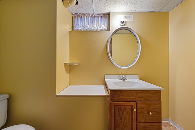 bathroom with toilet, a paneled ceiling, and vanity