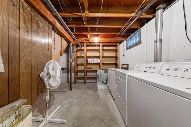 clothes washing area featuring washing machine and clothes dryer and wood walls