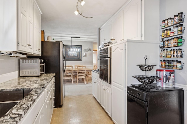 kitchen with appliances with stainless steel finishes, white cabinetry, stone countertops, and decorative light fixtures