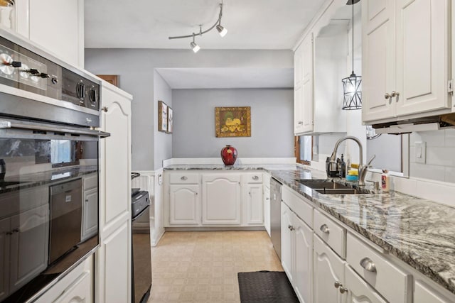 kitchen with kitchen peninsula, light stone countertops, decorative light fixtures, white cabinetry, and sink