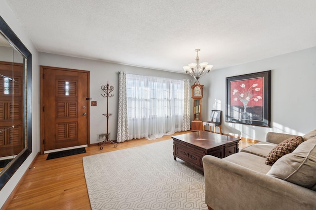 living room with a textured ceiling, a notable chandelier, and light hardwood / wood-style flooring