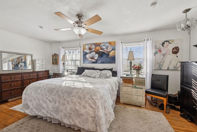 bedroom featuring a textured ceiling, ceiling fan, and light hardwood / wood-style flooring