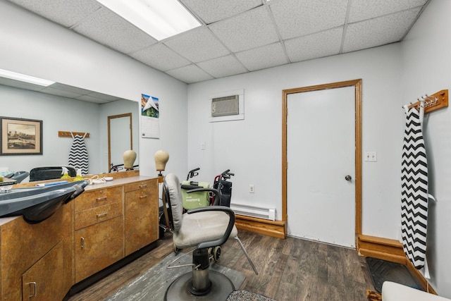 office area featuring a wall mounted AC, a drop ceiling, a baseboard radiator, and dark hardwood / wood-style flooring