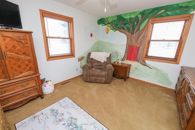 living area with ceiling fan and carpet