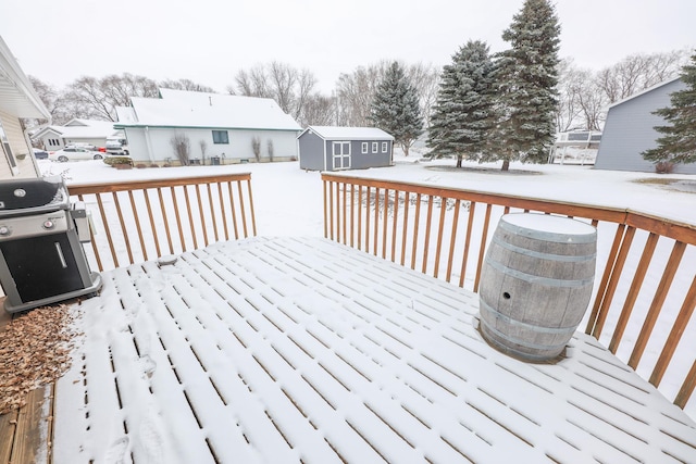 snow covered deck featuring grilling area and a storage unit