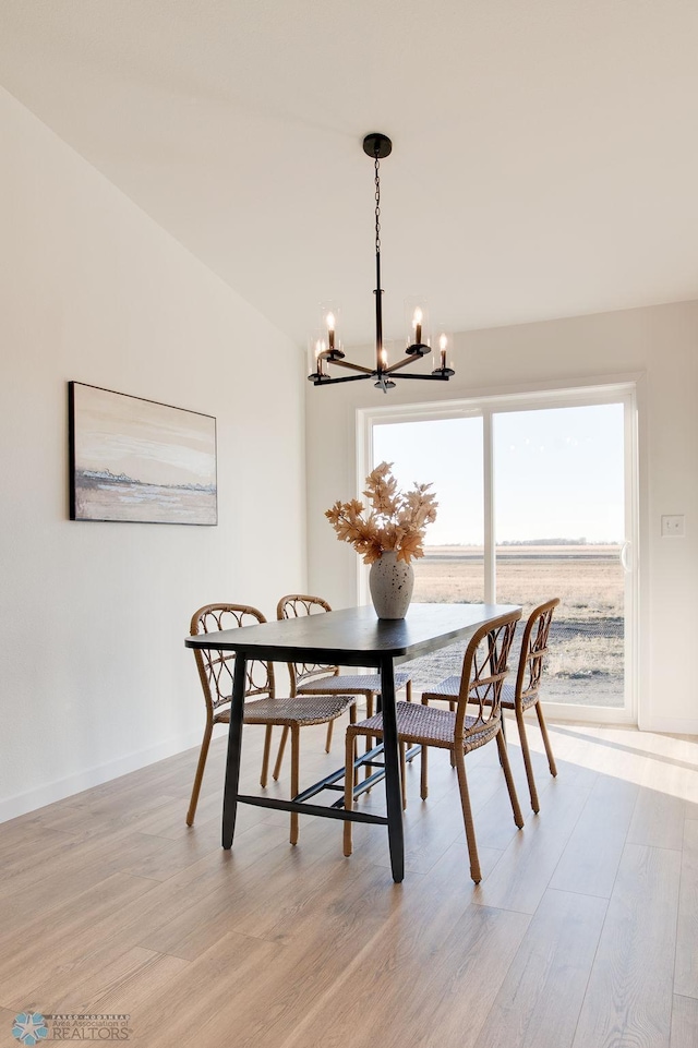 dining area featuring vaulted ceiling, a water view, light hardwood / wood-style flooring, and a chandelier