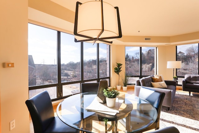 dining room featuring plenty of natural light, expansive windows, visible vents, and wood finished floors