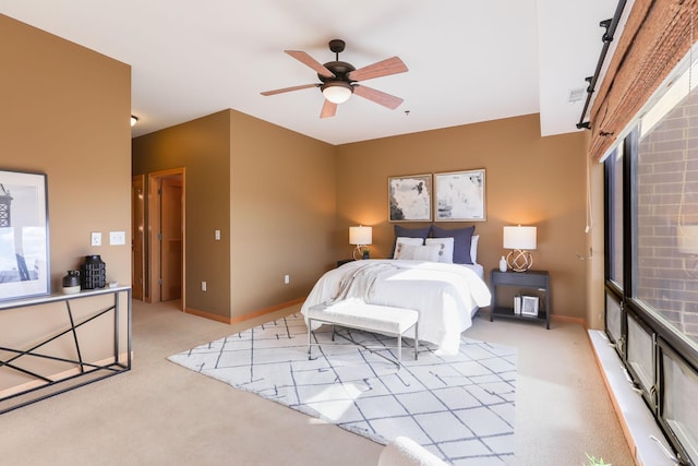 bedroom with ceiling fan, baseboards, and light colored carpet