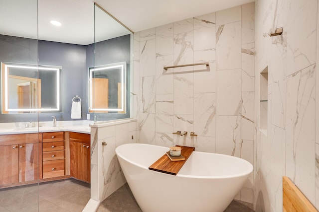 full bath featuring double vanity, tile walls, a freestanding bath, and recessed lighting