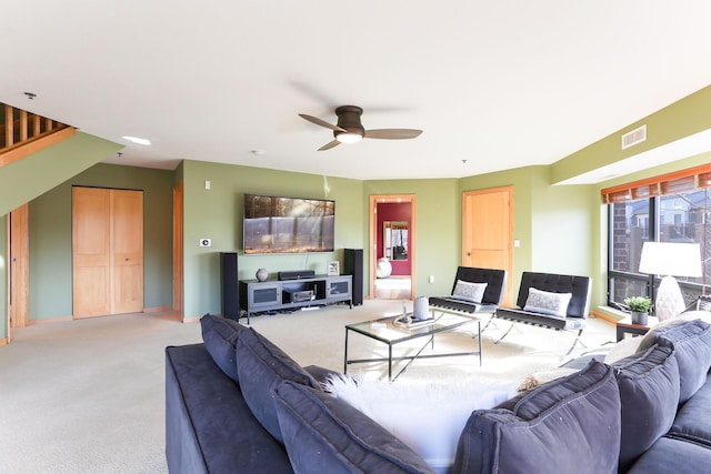 living area featuring baseboards, visible vents, a ceiling fan, and light colored carpet