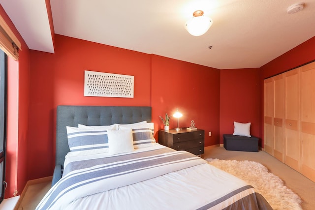 carpeted bedroom with a closet and baseboards