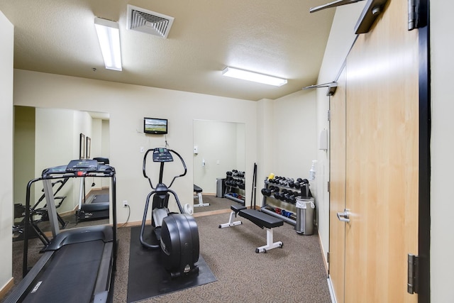 exercise room featuring baseboards, visible vents, and a textured ceiling