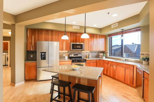 312 Spring St Unit 309, Saint Paul, MN 55102 - kitchen with stainless steel appliances, washer and dryer, light wood finished floors, decorative backsplash, and light stone counters