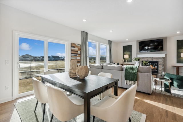 dining space featuring a stone fireplace and light wood-type flooring