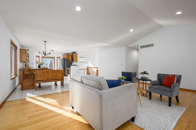 living room with lofted ceiling, a chandelier, and light hardwood / wood-style floors