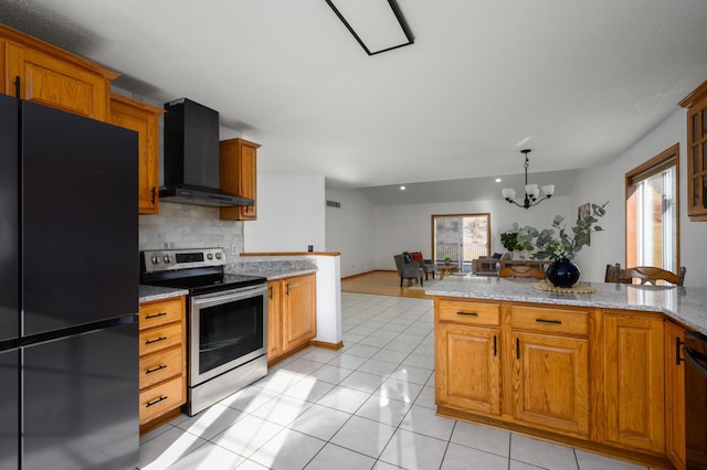 kitchen with wall chimney exhaust hood, stainless steel range with electric cooktop, black fridge, light stone counters, and a wealth of natural light