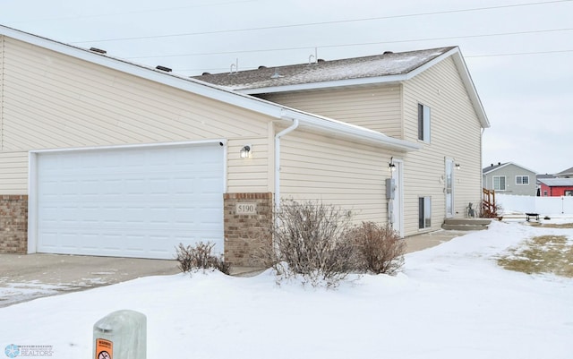 snow covered property featuring a garage