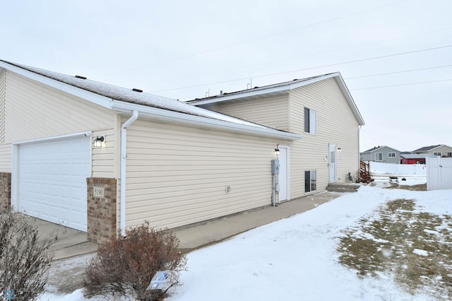 view of snowy exterior featuring a garage