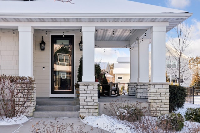 snow covered property entrance with a porch