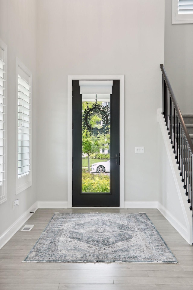 foyer entrance with visible vents, stairs, baseboards, and wood finished floors