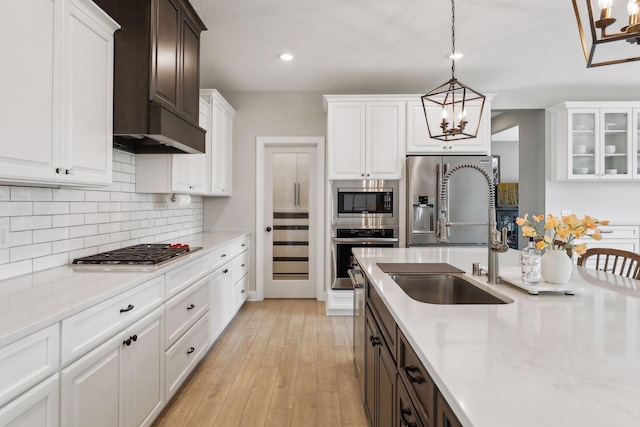 kitchen featuring stainless steel appliances, white cabinetry, a sink, and backsplash