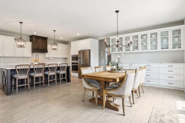 dining space featuring light wood-type flooring, a notable chandelier, and recessed lighting