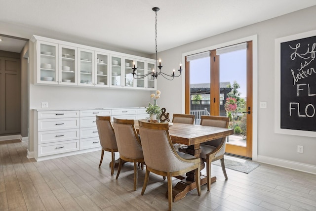 dining room featuring light wood-style flooring, baseboards, and a chandelier