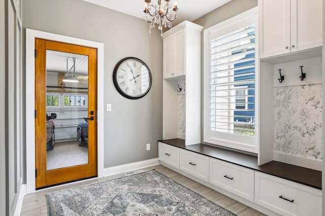 mudroom with baseboards, light wood-type flooring, and an inviting chandelier