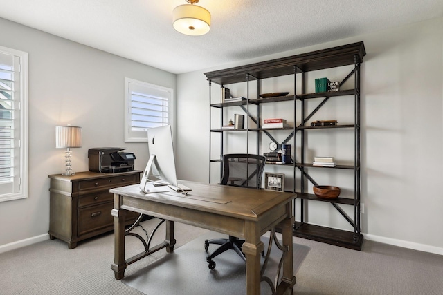 office space with light carpet, baseboards, and a textured ceiling