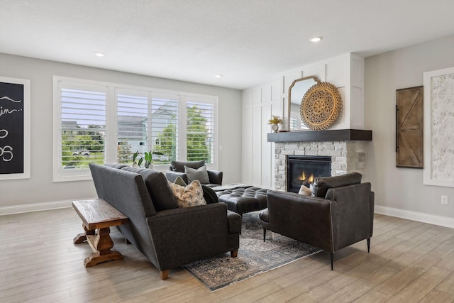 living room with light wood-type flooring, a fireplace, baseboards, and recessed lighting