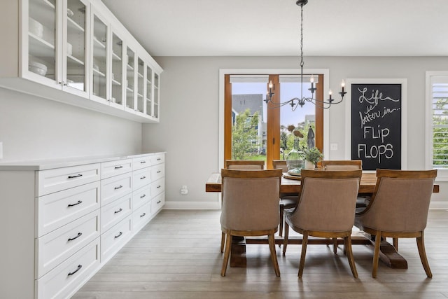 dining space with a chandelier, light wood finished floors, and baseboards